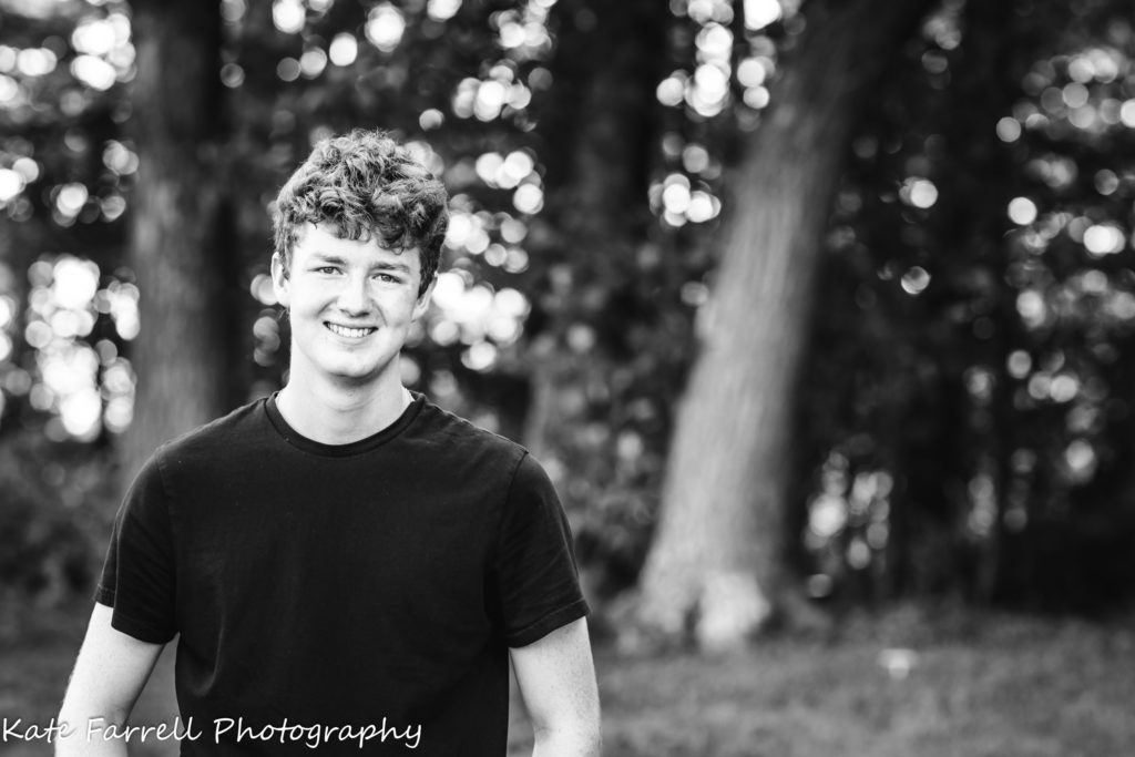 Black and white photo of smiling young man at senior photo session in Williston, VT