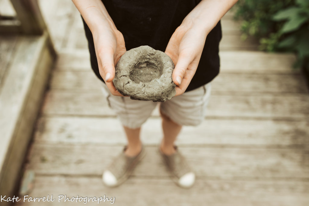 10 year old Vermont boy holds a clay pot he made.

