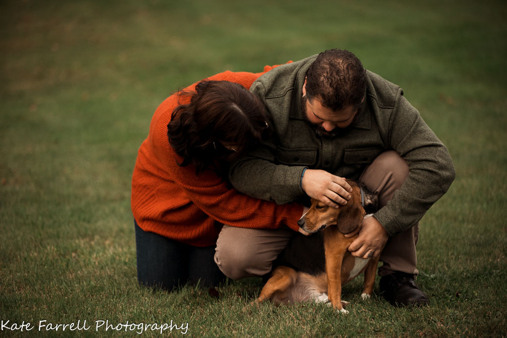 Dad and teenage daughter hug their beagle in the yard. Example of a lifestyle family picture. 