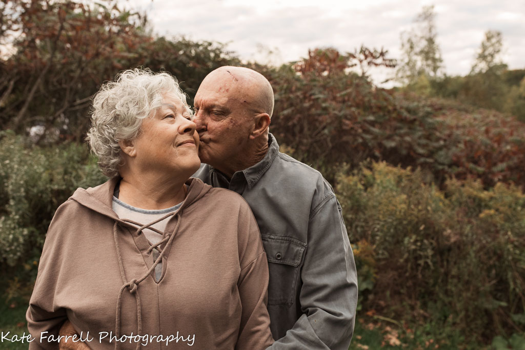 Grandparents kissing outside.