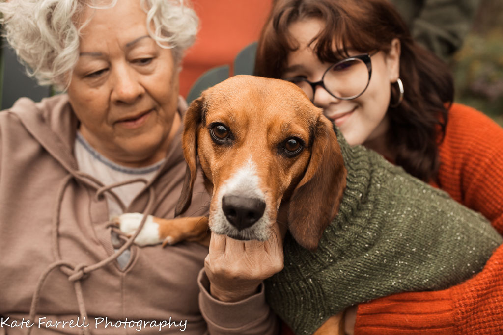 Grandma sits with teenage daughter and a beagle on her lap.
