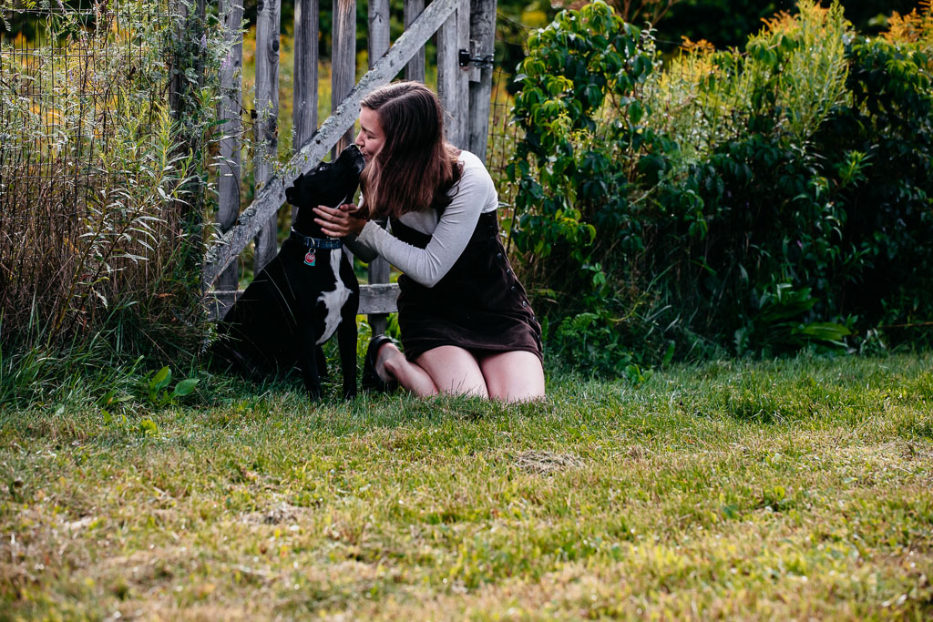 A black and white dog gives big kisses to her teenaged human girl -- Vermont Dog photography