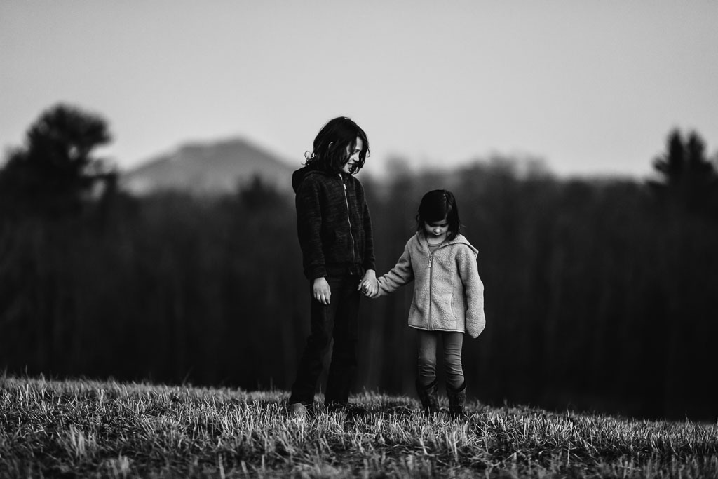 Brother and Sister at a family photo session -- holding hands in front of a mountain.
