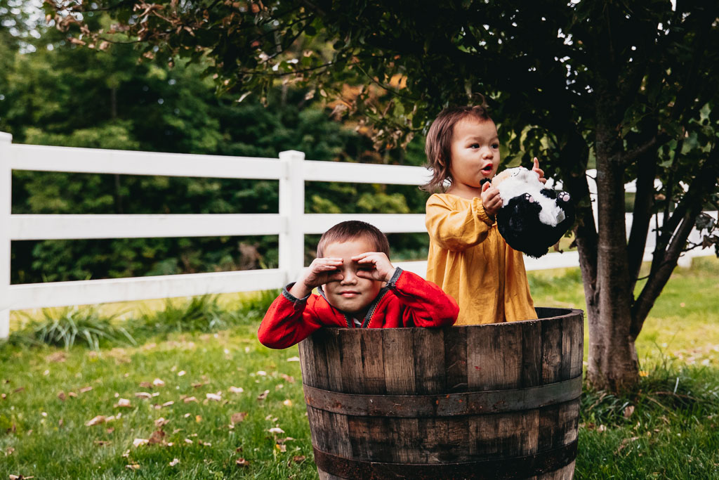Two toddlers pretending to sail a ship in an old whisky barrel Vermont Family Photo Sessions