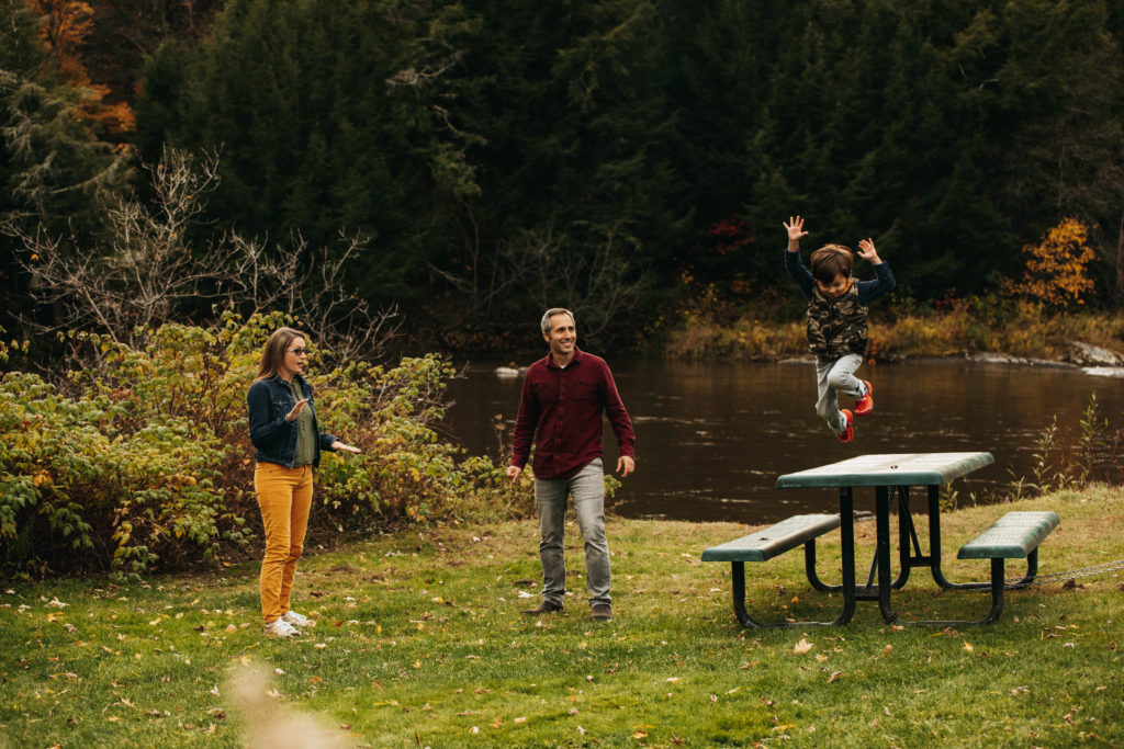 vt photography -- a family photo session at a park. Little boy is having fun jumping off a picnic table.