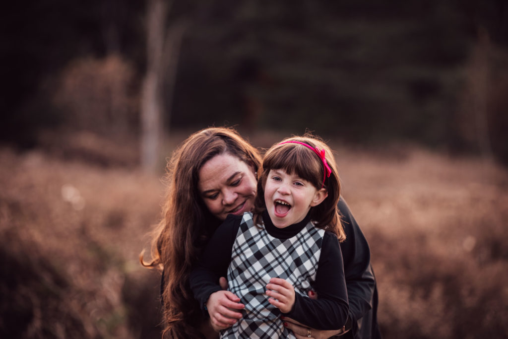 A mom hugs her daughter who is laughing happily -- a fun example of family photography.
