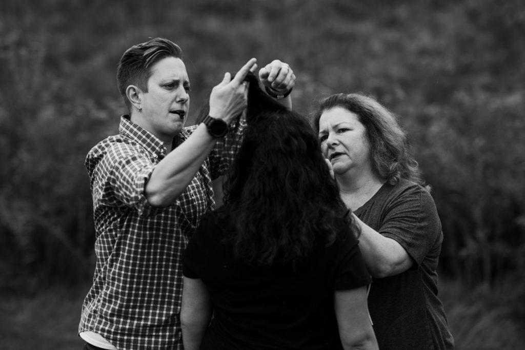 Two moms fix their daughter's hair in preparation for her photo session.