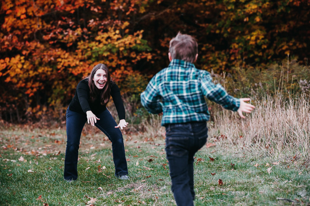 simple family photo of a son running to his mom's open arms in the fall