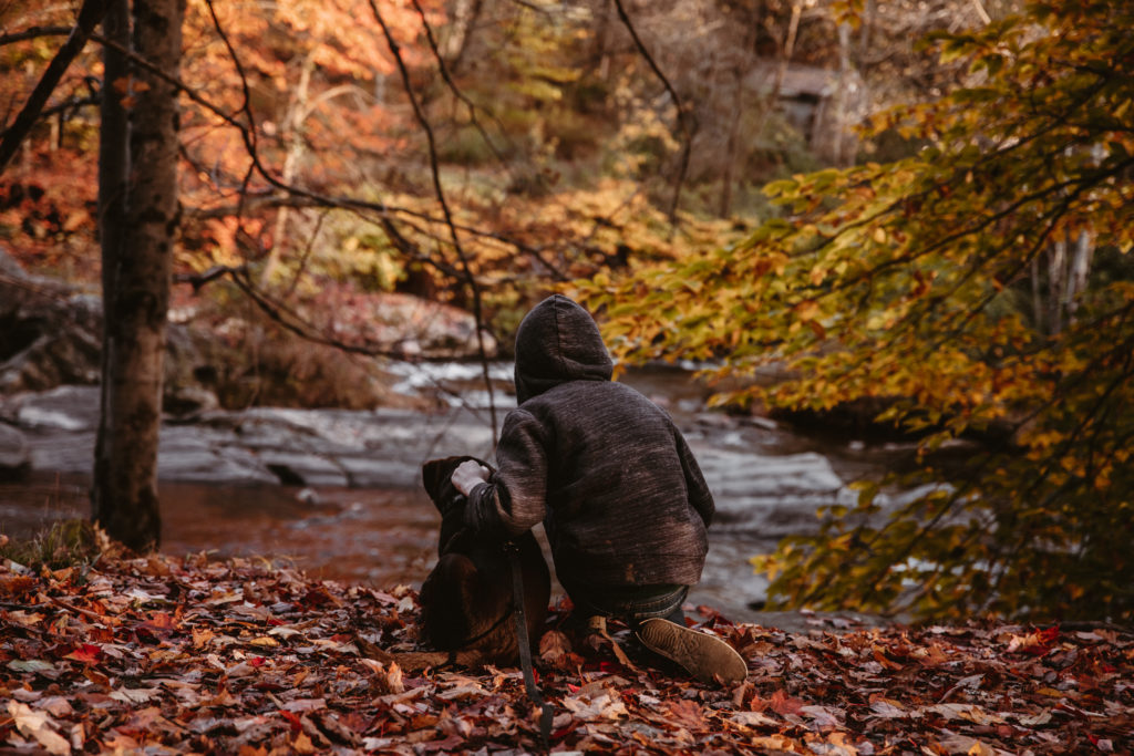 Home school kid at a river with his dog.