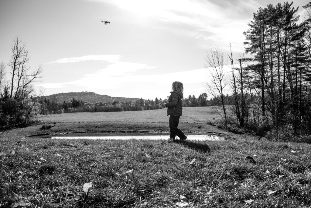 A kid playing with a drone in black and white.