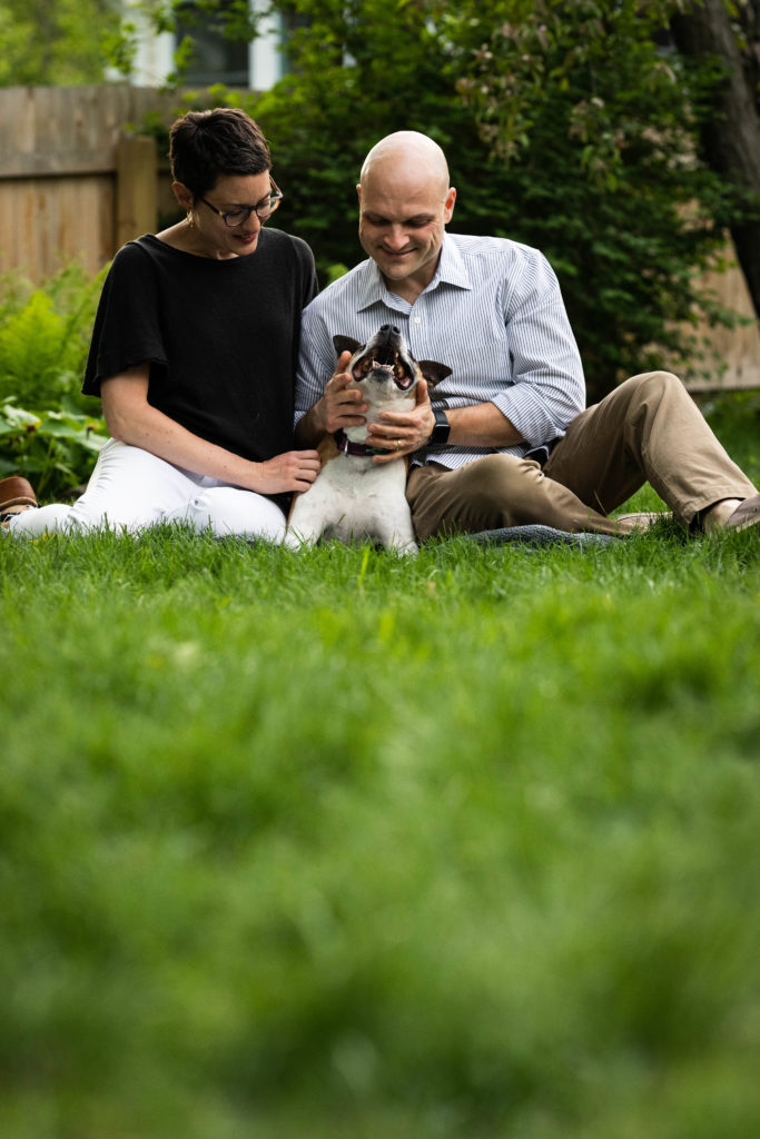 Young couple sitting in the grass with their beloved dog. 