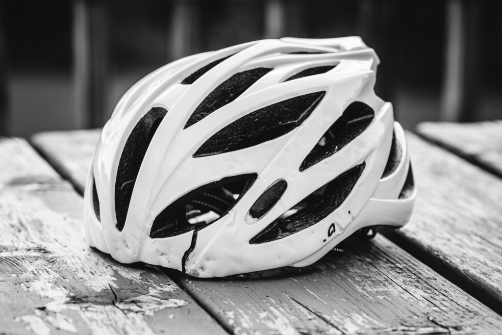 Black and white image of a cracked cycling helmet. 