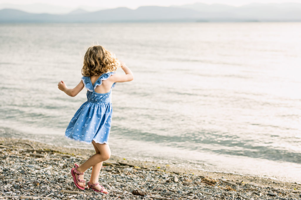 A 4 year old girl spinning her dress on the beach.