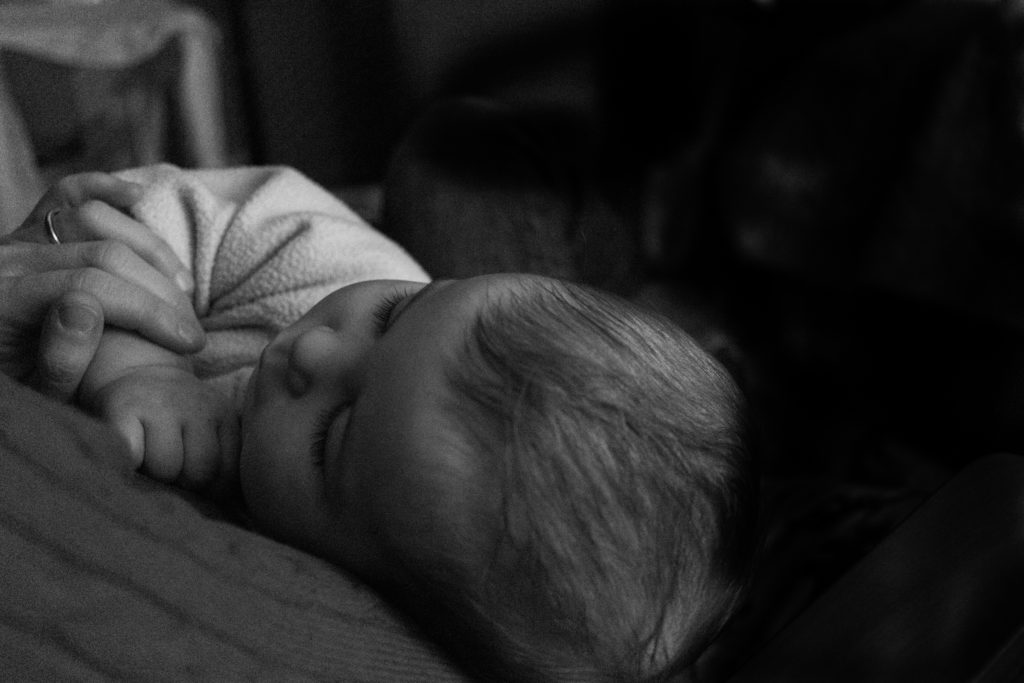 A black and white image of a mother holding a sleeping baby.
