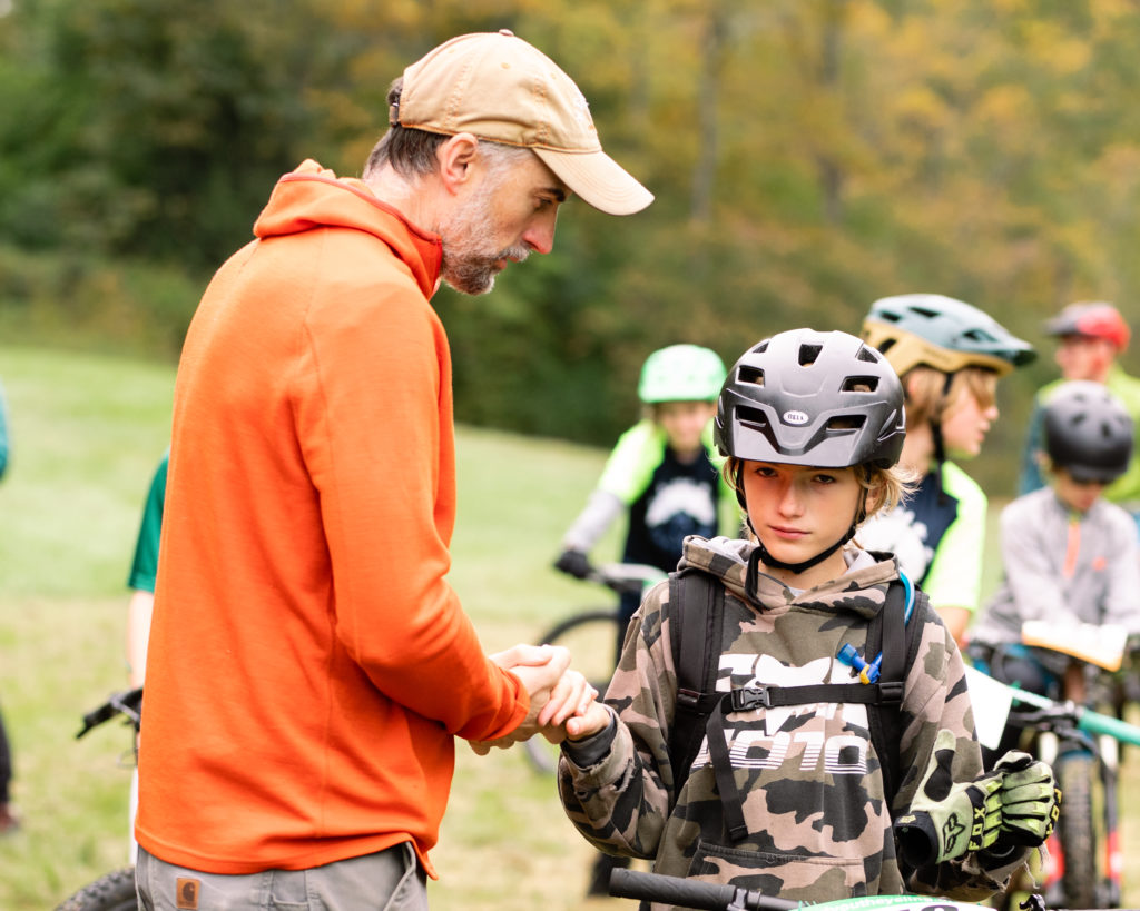 Vermont Youth Cycling at Woodstock 2022 - Dad warms son's hands on the start line.