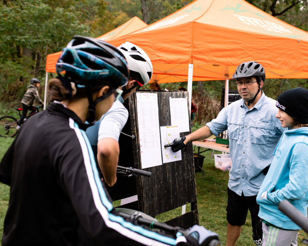Vermont Youth Cycling at Woodstock 2022 - coach helps riders study the course map.