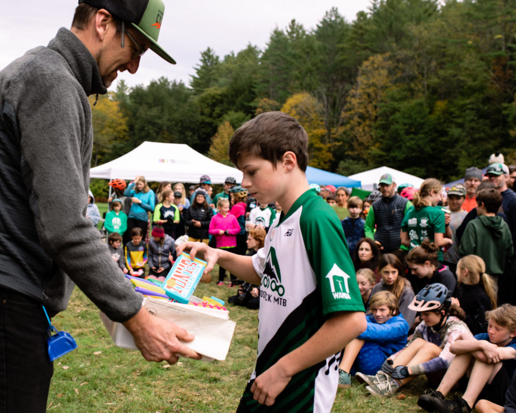 Vermont Youth Cycling at Woodstock 2022 -- racer picks his chocolate before climbing to the podium