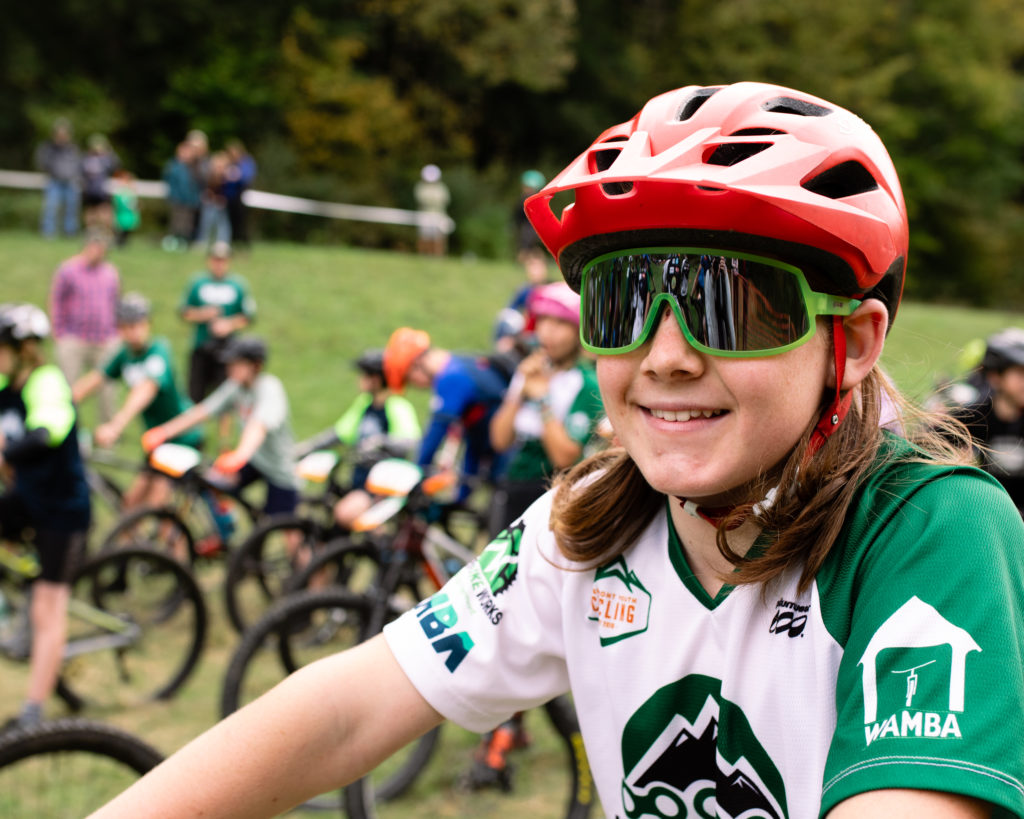 Vermont Youth Cycling at Woodstock 2022 pre-race portrait of a girl wearing a red helmet and sunglasses