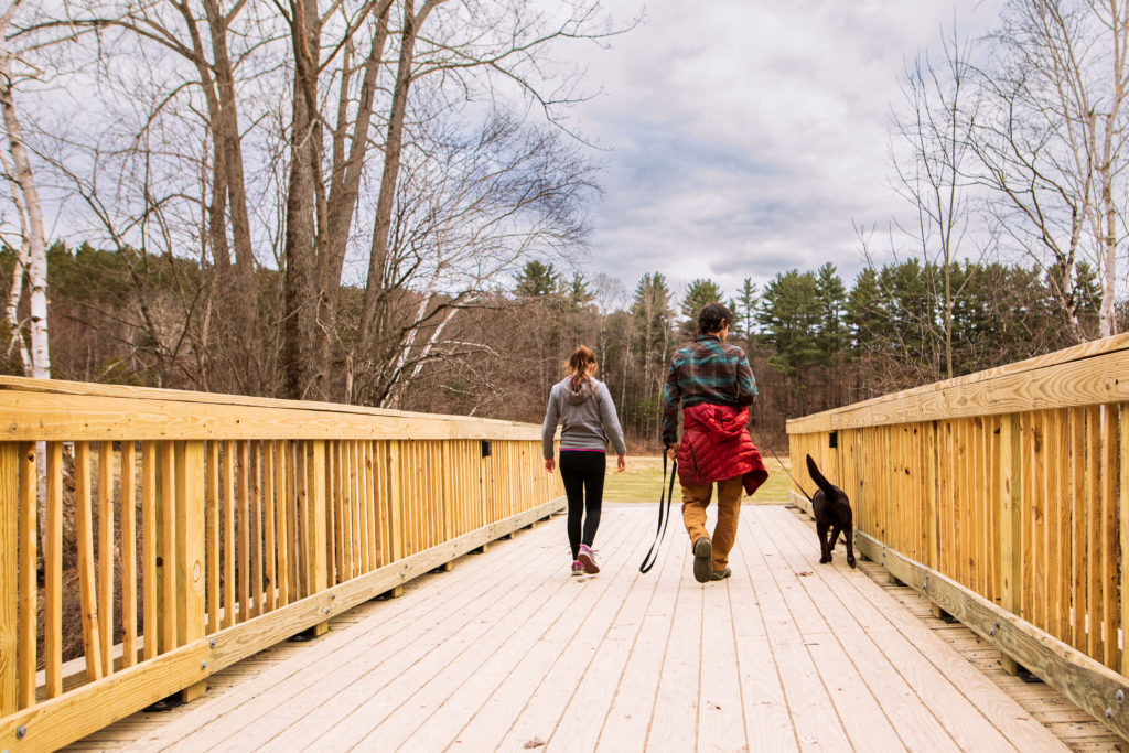 Father and daughter walking their dog on a bridge. Family photo in Williston Vermont.
