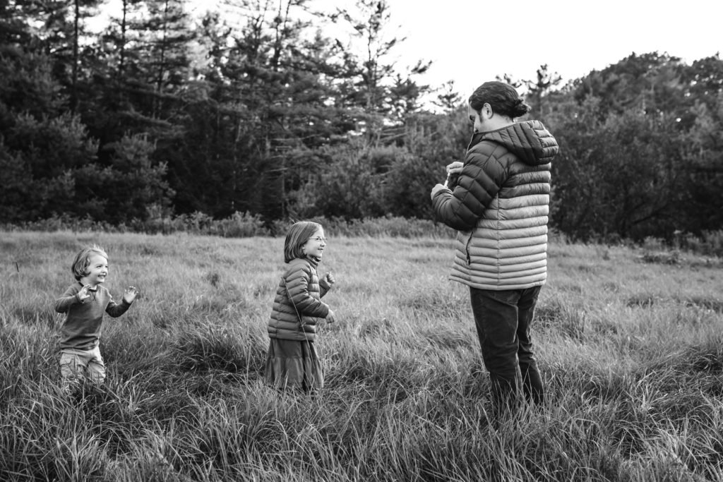 Dad blowing bubbles for the kids to chase in a field of tall grass - Vermont Outdoor Family Photography