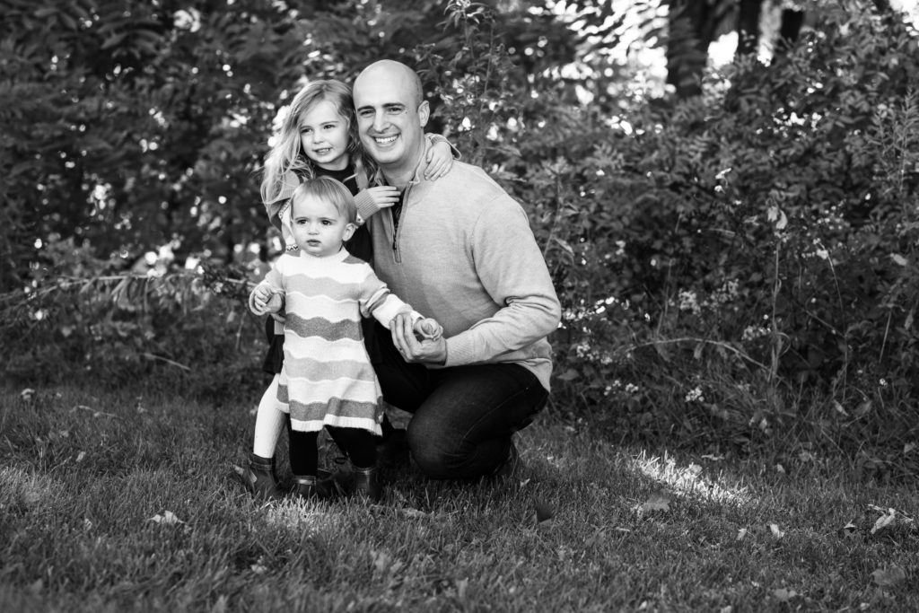 Black and white image of Dad hugging is 2 and 4 year old daughters