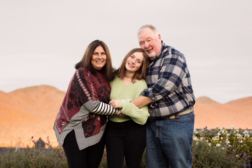 Mom and Dad hug their teenage daughter on a beautiful fall day - Vermont Family Photography Session
