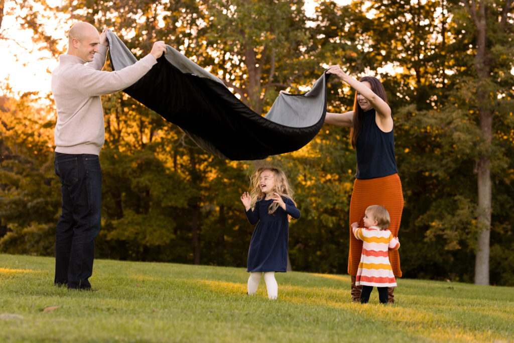 Mom, Dad and two young kids get ready to sit on a blanket at a Vermont family Family portrait session.