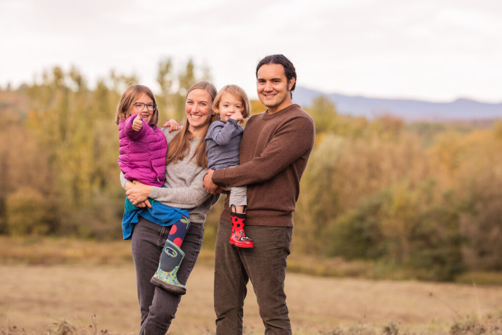 A family of four smiles with the Green Mountains of Vermont in the background. 