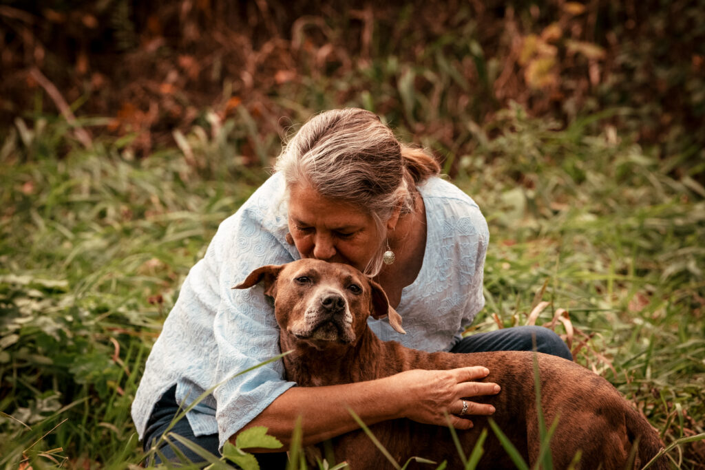 A woman gives her dog a hug in the fall.