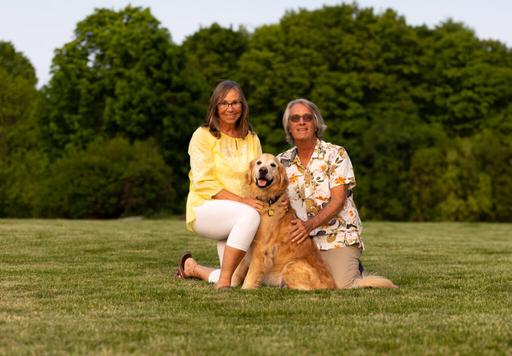 Portrait of a Vermont couple with their older golden retriever. 