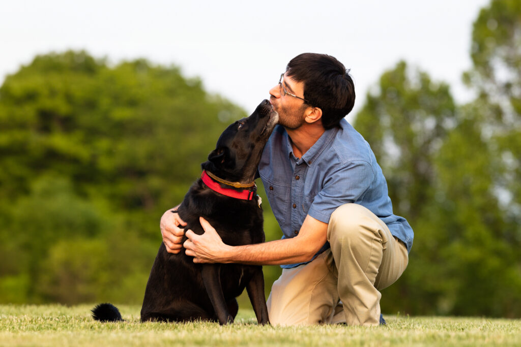 Vermont dog photography -- a man gets a big kiss from his black dog.
