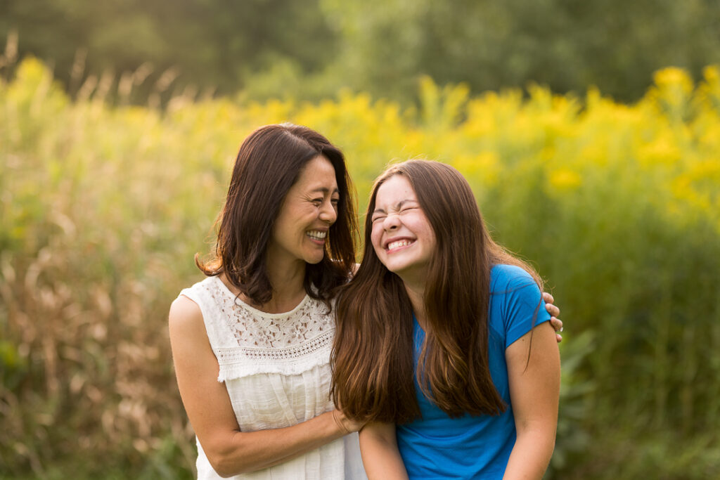 Mom and teen daughter laughing at a late summer family photo session in Vermont.