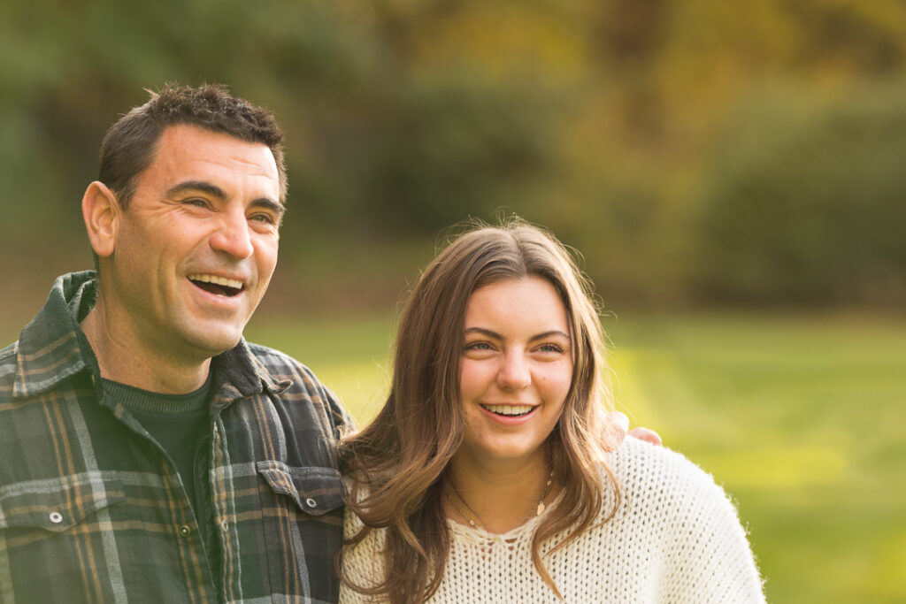 Dad and teen daughter share a laugh during a late fall Vermont family photo session.